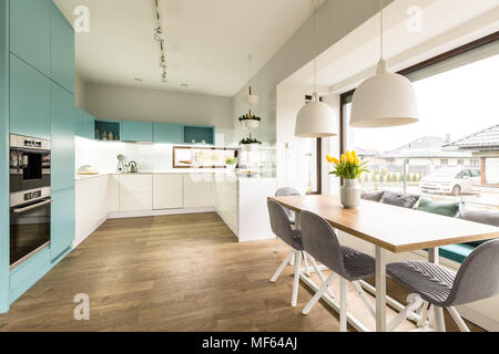 Bianco e blu interni di cucina con un grande tavolo da pranzo, sedie e finestra Foto Stock