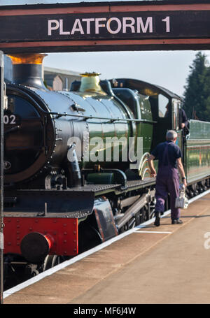 Focus sulla piattaforma 1 segno sopra gateway di SVR vintage stazione ferroviaria, Kidderminster. Vapore stazionaria loco in background, frontale e laterale che mostra. Foto Stock