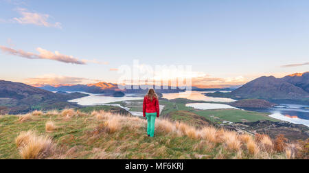 Escursionista affacciato sul lago Wanaka e montagne, tramonto, picco roccioso, Glendhu Bay, Otago Southland, Nuova Zelanda Foto Stock
