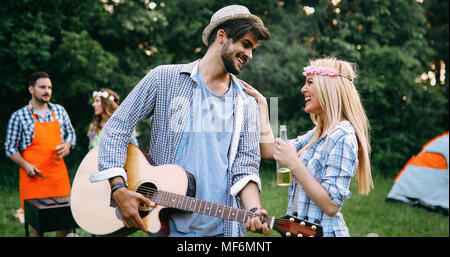 Uomo bello suonare la chitarra alla sua ragazza in natura Foto Stock