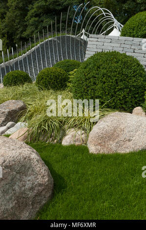 Drammatica scultura di metallo, pietre bianche, erbe & buxus rappresentano le onde & litorale - 'Wave Dance' giardino, RHS Flower Show, Tatton Park, Inghilterra, Regno Unito. Foto Stock