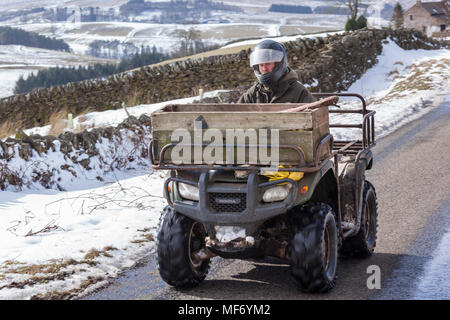 Un agricoltore su di una moto quad in inverno la neve sui Pennines vicino a Alston, Cumbria Regno Unito Foto Stock