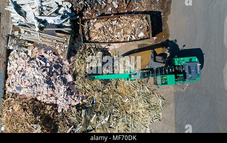 Foto aerea di una gru con un artiglio enorme davanti a un legno mucchio degli scarti Foto Stock