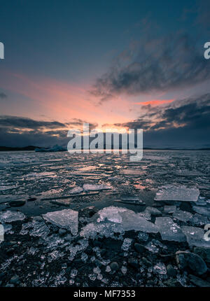 Colorato tramonto Immagine di Jokulsarlon laguna glaciale in Islanda con dei pezzi di ghiaccio e montagne Foto Stock