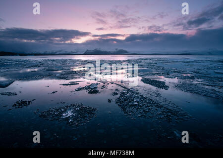 Colorato tramonto Immagine di Jokulsarlon laguna glaciale in Islanda con dei pezzi di ghiaccio e montagne Foto Stock