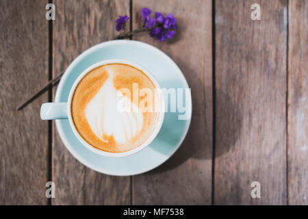 Vista superiore del caffè caldo in tazza verde con latte art su tavola in legno tavolo con Non ti scordar di me flower,cibo e bevande concetto,filtro vintage Foto Stock