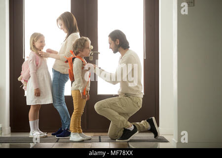 I genitori aiutano i bambini la preparazione di andare a scuola a piedi presso il padiglione Foto Stock