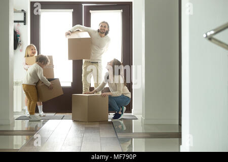 La famiglia felice con bambini e scatole in movimento nella nuova casa Foto Stock