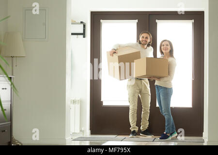 Eccitato giovane scatole porta entrando in casa in movimento nella nuova hom Foto Stock