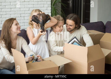 I bambini per aiutare i genitori di disimballare le caselle insieme in movimento nella nuova casa Foto Stock