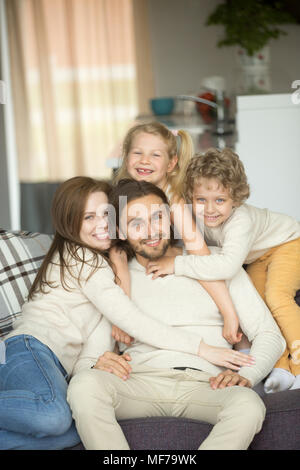 La famiglia felice con bambini sul divano guardando la telecamera, ritratto Foto Stock
