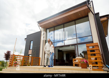 Felice coppia giovane abbracciando permanente sulla casa di lusso porc anteriore Foto Stock