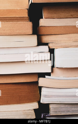 Disordinato di pile di vecchi e nuovi libri, telaio di riempimento. Retrò filtrato in toni caldi. Foto Stock