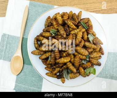 La cucina e il cibo tailandese tradizionale profondo fritto marinato vermi di noce di cocco con erbe su un piatto bianco. Uno dei più popolari street food in Thailandia. Foto Stock