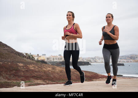 Due belle ragazze in esecuzione in abiti fitness su un giorno di estate in riva al mare Foto Stock