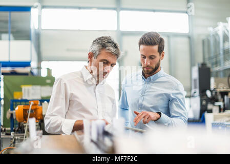 Uomini d'affari durante la riunione con la compressa nella sala di produzione Foto Stock