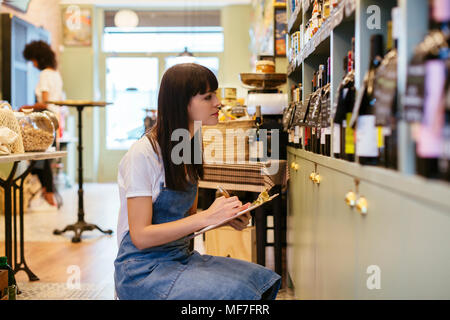 Donna con appunti a scaffale di un negozio Foto Stock