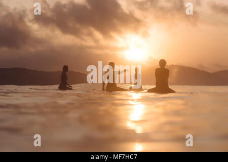 Indonesia, Lombok, gruppo di surfers seduto su tavole da surf al tramonto Foto Stock