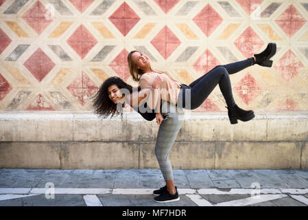 Ridendo donna che porta il suo migliore amico piggyback Foto Stock