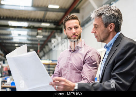 Imprenditori con il piano durante la riunione nella sala di produzione Foto Stock