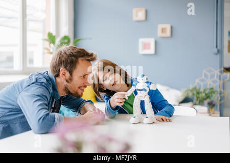 Felice padre e figlio giocare con il robot sulla tabella a casa Foto Stock