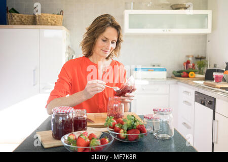 Donna fare confettura di fragole in cucina a casa Foto Stock