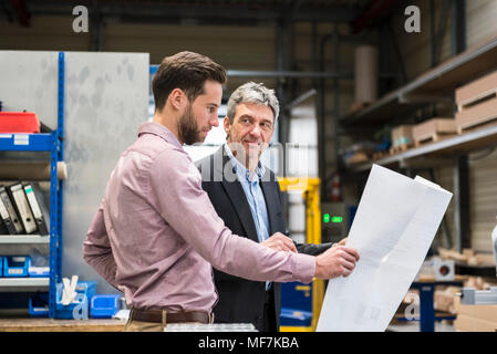 Imprenditori con il piano durante la riunione nella sala di produzione Foto Stock