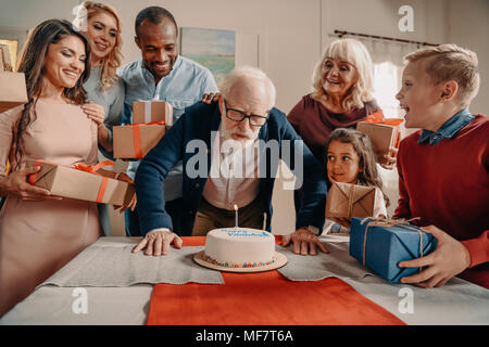 L'uomo soffiando candela sulla torta di compleanno Foto Stock