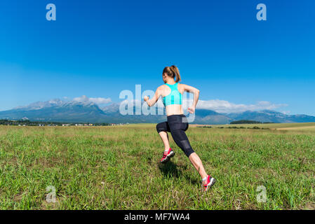 Ragazza Fitness lavorando sul campo verde nelle Alpi Foto Stock