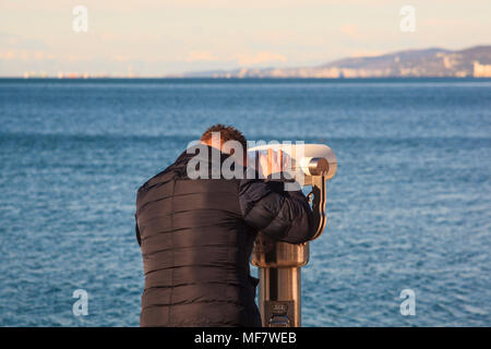 TRIESTE, ITALIA - Dicembre, 17: l'uomo cerca attraverso un binocolo turistico vicino al mare a Trieste su dicembre 17, 2017 Foto Stock