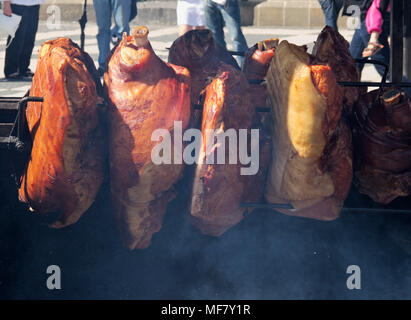 Di maiale affumicato Prosciutto gambe la grigliatura in via del mercato alimentare a Praga, Repubblica Ceca Foto Stock