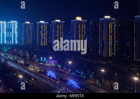 Guardando sul grattacielo illuminato costruire in una riga e di un'autostrada di notte, Shenyang, Cina Foto Stock