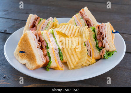 Affettato Triple Decker Turchia Club Sandwich Deli su una piastra con patate fritte Foto Stock