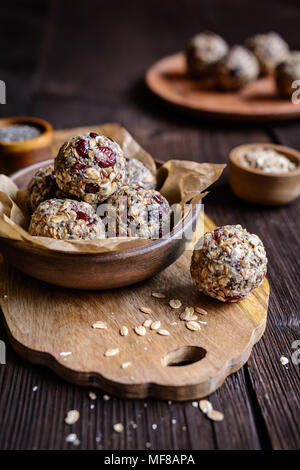 Un sano materie i fiocchi d'avena sfere con semi di Chia, mirtilli rossi secchi, cocco grattugiato, semi di lino e miele Foto Stock