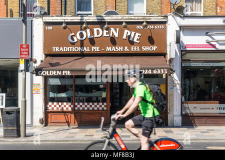 Ciclista, movimento sfocato, in sella a una moto di Santander passato il Golden Torta tradizionale & Mash eel pie shop a Clapham Junction. Foto Stock