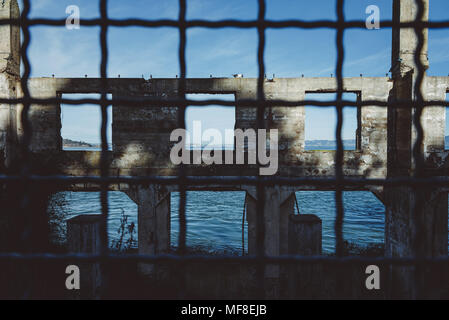 I resti di un edificio sull isola di Alcatraz visto attraverso una maglia a filo Foto Stock