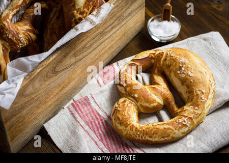 Pretzel con sale marino su rustico sfondo di legno Foto Stock