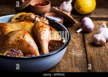 Pollo arrosto con aglio, timo e limone nella padella di cottura rustico sfondo di legno Foto Stock