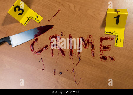 La parola "crimine" scritto nel sangue su di una superficie di legno accanto a un coltello insanguinato, sia segnata da prove di scene del crimine marcatori. Foto Stock