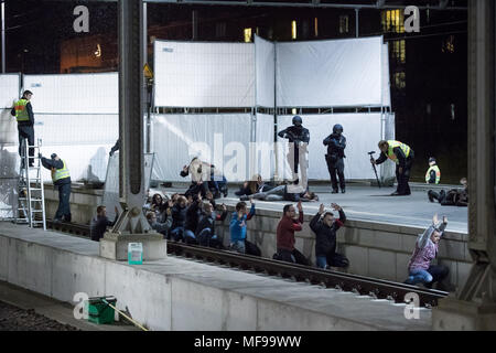 24 aprile 2018, Germania, Lubecca: gli ufficiali di polizia e gli astanti in piedi su una piattaforma nel corso di una dimostrazione di stampa per un anti-terrorismo esercizio a Lubecca stazione. Quasi 700 funzionari di polizia di stato e paese nonché circa 120 task force dei vigili del fuoco e i servizi di emergenza stanno prendendo parte a questo esercizio presso la stazione principale. Foto: Christian Charisius/dpa Foto Stock