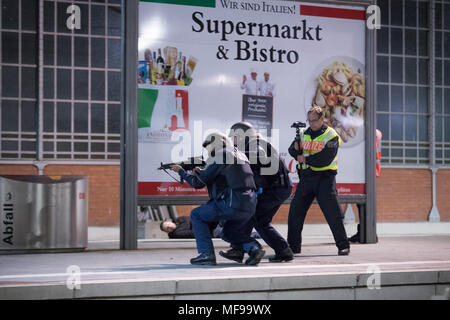 24 aprile 2018, Germania, Lubecca: gli ufficiali di polizia e gli astanti a piedi attraverso una piattaforma durante una dimostrazione di stampa per un anti-terrorismo esercizio a Lubecca stazione. Quasi 700 funzionari di polizia di stato e paese nonché circa 120 task force dei vigili del fuoco e i servizi di emergenza stanno prendendo parte a questo esercizio presso la stazione principale. Foto: Christian Charisius/dpa Foto Stock