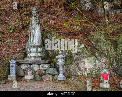 Statua di Kannon Bosatsu con red bib e Jizo ishidoro lanterna di pietra, Shosanji Tokushima, Shikoku Giappone Foto Stock