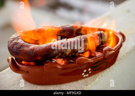 Tradizionale chourico portoghese o spagnolo il chorizo preparato in una speciale pentola di creta sul consumo di alcol Foto Stock