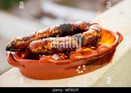 Tradizionale chourico portoghese o spagnolo il chorizo preparato in una speciale pentola di creta sul consumo di alcol Foto Stock