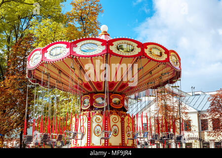 Giostra vuota Merry-Go-Round con sedili sospesi su catene senza persone in attesa per i suoi visitatori. Attrazioni in autunno, chiusura di attractio Foto Stock