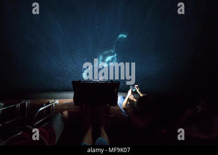 Manta ray, Mobula alfredi, mangia plancton di notte dietro la barca mentre la gente guarda Foto Stock