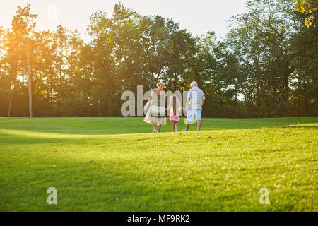 La gente che camminava sul prato verde. Senior l uomo e la donna, nipote. Foto Stock