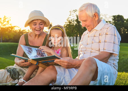 La gente cerca attraverso album di foto. Ragazza caucasica con i nonni all'esterno. Pagine del passato. Foto Stock