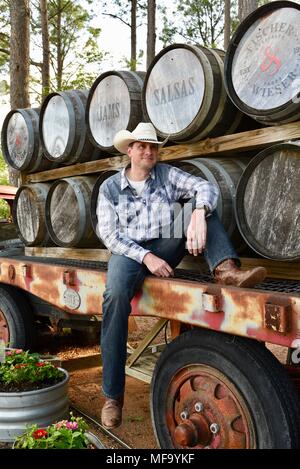 Western cowboy seduti sul rimorchio dello scanner a superficie piana con il whisky botti o barili a Pesche Das Haus, Fredericksburg, Texas, Stati Uniti d'America. Foto Stock