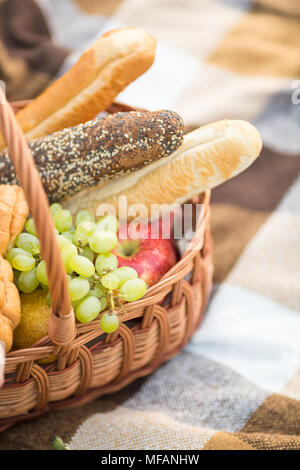 Trattamento, cibo, concetto di alimentazione. close up del cesto per pic-nic che è piena di deliziose prelibatezze, come diversi tipi di pane e focaccia lungo, rosso Foto Stock